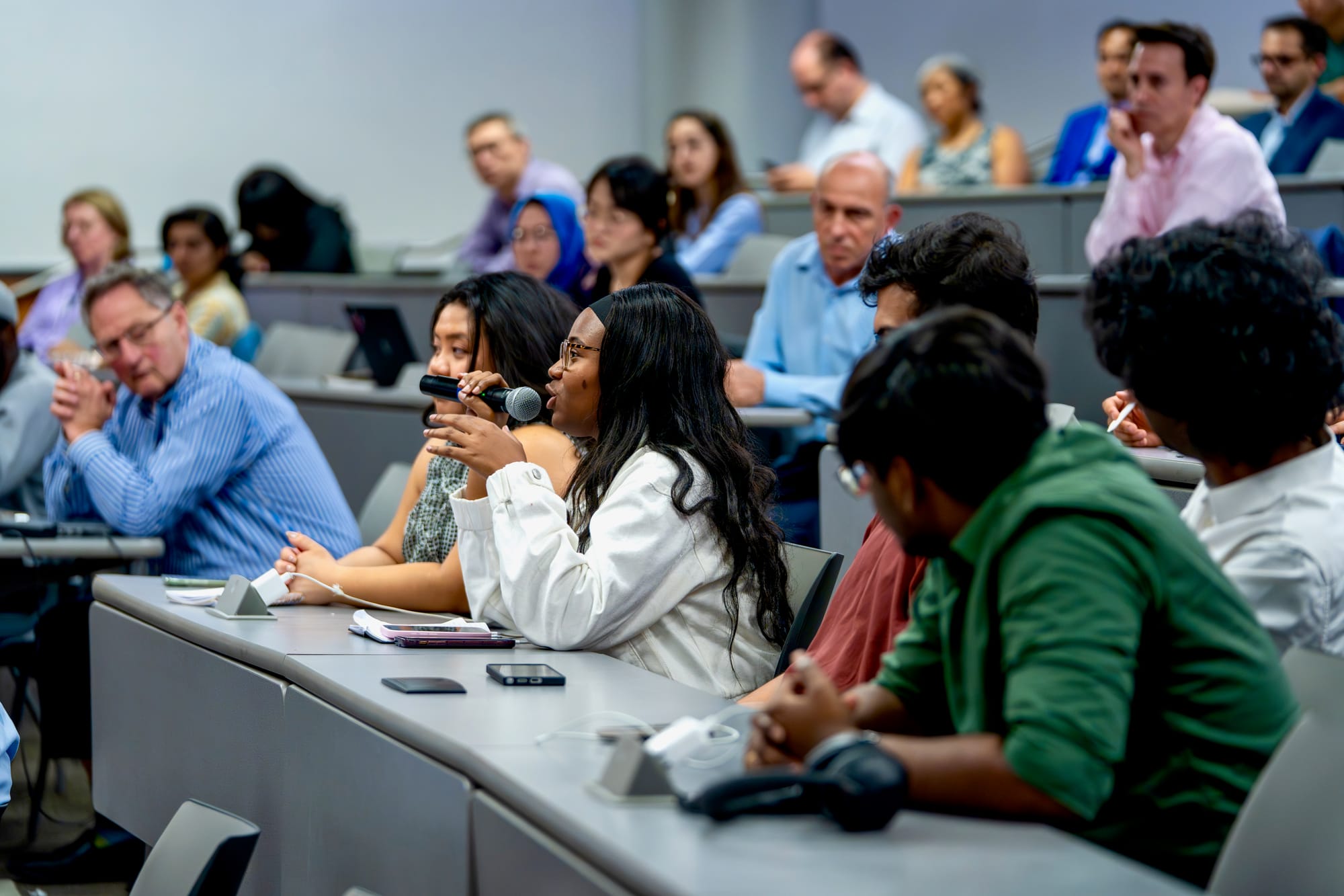 Audience in a lecture hall at the Business+AI Forum as a participant asks a question into a microphone