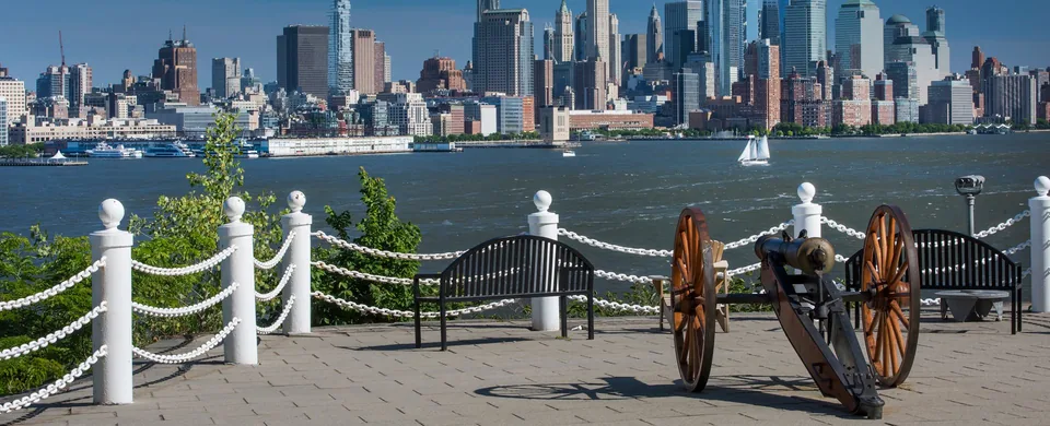 Castle Point lookout: a cannon, benches and chain railing above the Hudson, Manhattan across the water