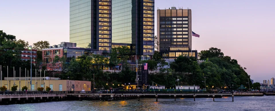 Stevens campus seen from the Hudson at dusk: the University Center Complex towers above the waterfront pier